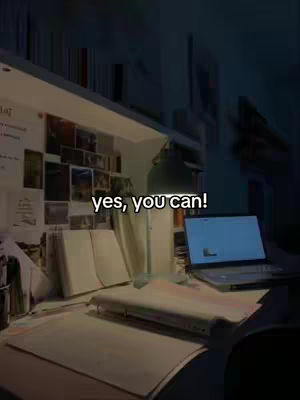 A dimly lit desk with a laptop, books, and papers. A desk lamp is on, illuminating the workspace where there is text overlayed on top.