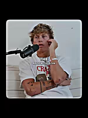 The cover image presents a young man in a white t-shirt, seated and facing the camera. He holds his hand near his face and there's a microphone positioned near his mouth. Text overlays are present, one at his left arm, one beside his wrist and one at the mid-top of the image