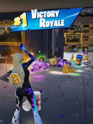 The image is a screenshot from the Fortnite game, depicting a victorious player. The game interface has '#1 Victory Royale' displayed on a banner with a blue gradient background. The player character is a female avatar with blonde hair, wearing a dark outfit with colorful patterns. She is positioned in a celebratory pose. The background shows the interior of what appears to be a game location and is littered with various items, including weapons. The overall composition is vibrant, with a focus on the triumphant player.