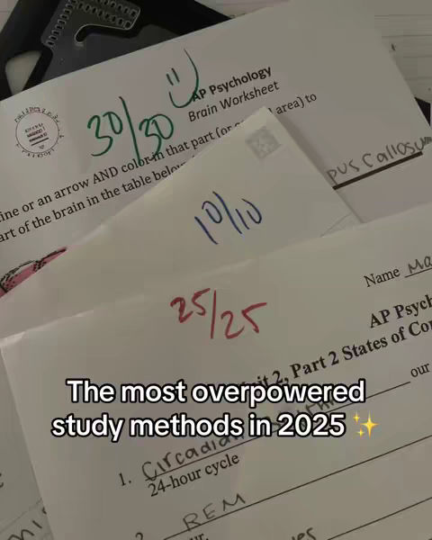 Close-up shot of several sheets of paper with handwritten notes and scores. The papers are white with blue and green ink markings, featuring an AP Psychology worksheet marked 30/30 with a smiley face. Below, text in a white box states 'The most overpowered study methods in 2025', with a list of study techniques below.