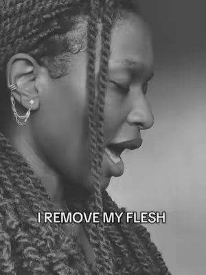 A black and white photo of a woman with her eyes closed and mouth open, as if she were singing or in a moment of emotional expression. She has braids, and an earring is visible. The overlay text at the bottom reads "I REMOVE MY FLESH".