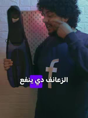 The cover image features a man holding a diving fin. He is wearing a dark blue shirt with a white 'f' logo that appears to be related to the social media platform Facebook. The background has a mix of colors with a white brick wall and something pink or red in the corner. There is text overlayed on the cover image: 'الزعانف دي ينفع', which has a purple background. The layout is simple with the man being the central figure.