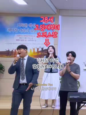 The image shows three people on a stage with microphones. A man in a suit is on the left, a woman in a white skirt and a jacket is in the center, and another man in a gray shirt is on the right. Text overlays include Korean phrases and the English phrase "I will praise You". The background suggests a church setting, with a banner.