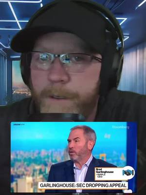 A man with glasses, a black hat and a headset is centered in the frame. Behind him is a blurred interior with blue and white. Below him is a screen with the video call of a man talking on Bloomberg. The Bloomberg segment features a news ticker and the words: "GARLINGHOUSE: SEC DROPPING APPEAL".
