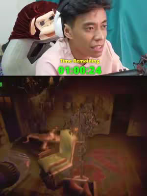 The cover image is split horizontally. The top half features a young, light-skinned man reacting to something off-screen to the right. He's wearing a pink t-shirt and a headset. Beside him, to the left, is a large plush of what appears to be a monkey head, partly obscuring a white headpiece.  Below the man is a dark, blurred game scene, with a green vertical timer overlayed.
