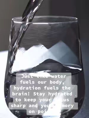 A glass of water is being filled from above against a dark background. The water stream is clear. Text overlayed on the glass in a white rectangular block spells out a message about hydration.