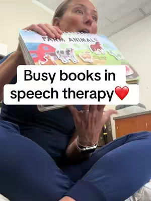 A woman sits cross-legged, holding a children's book open and close to the camera, overlaid with text. The background is a nondescript interior possibly a room.