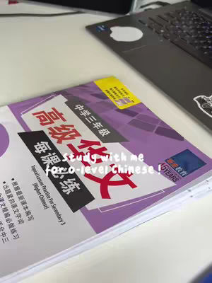 A close-up shot shows a desk with a laptop in the background on the right, and a partially visible textbook with purple and white cover on the left side. The textbook is open and has Chinese characters and the text "Study with me for O-level Chinese!" is overlaid on the book.