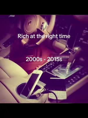 The inside of a car with a focus on the center console and dashboard. A phone is plugged into the charger in the center console. There's a steering wheel in the upper part of the frame. The overall lighting is dim and the color is desaturated with the text overlayed.