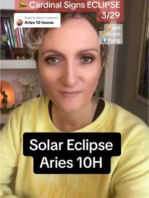 A woman with curly blonde hair is centered in a selfie-style shot, set against a blurred background of a room with a bookshelf. Overlay text in red, black, and white colors highlights keyphrases related to astrology and a solar eclipse.