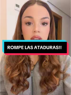 A woman with long, wavy auburn hair and light makeup looks directly at the camera. She is wearing a gray zip-up jacket. Overlaid on the image is a rectangular text box with the words "ROMPE LAS ATADURAS!!". The background appears to be a room with a door visible.