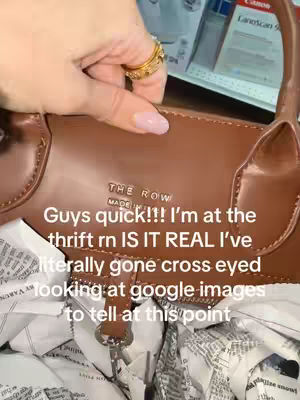 The foreground features a close-up shot of a brown leather handbag, possibly a The Row brand bag. The creator's hand, adorned with rings and nail polish, holds the bag. Newspaper or packing paper is crumpled underneath. The background is blurred, suggesting a store setting.