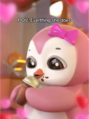 A close-up shot of a cartoon penguin-like character. The character has pink feathers, white cheeks, and a bright pink bow. The penguin is holding a small, gold-colored item that resembles an ice cream cone. The background is blurred, featuring soft pink and red heart shapes.