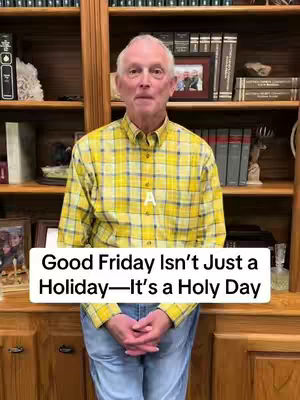 A medium shot features a man standing centered, hands clasped in front of him. He wears a yellow and blue plaid shirt and jeans, set against a backdrop of bookshelves with framed photos. He is looking at the camera directly.