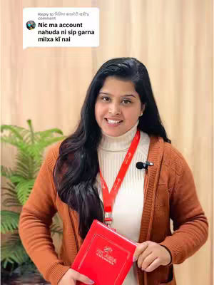 A woman with long black hair smiles at the camera, holding a red book and wearing a white turtleneck, a brown cardigan, and a red lanyard. A speech bubble with white text is in the top left corner, and there's a green plant in the background.