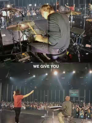 The image is split into two sections with a performance on a stage in the lower half. The top shows a drummer from behind, playing in front of a crowd. Below, a man in a red shirt conducts in front of a crowd, with another man at a keyboard. The text 'WE GIVE YOU' is overlaid on the image.