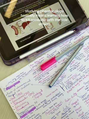 A top-down shot shows a notebook filled with handwritten notes and a tablet displaying a diagram related to pharmacology. A pink highlighter and two pens are placed on the paper as well. The notes cover the topic of pharmacology including a diagram of the liver. The tablet is set on top of the notes creating contrast. The overall composition highlights the theme of studying and education.