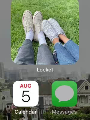 The image shows a phone screen with a top section displaying two pairs of feet, one pair in faded Converse sneakers and the other in light-colored ones, resting on green grass. Below the feet, a phone's home screen with an informational text about the Locket app overlayed the image. The home screen features a calendar icon displaying August 5th and a Messages app icon. The overall layout is clean, with a natural background contrasting with the digital interface elements.