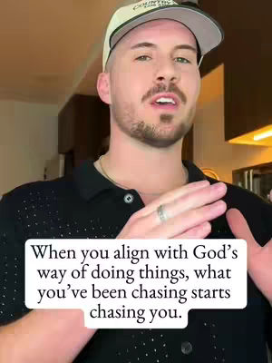 A man with a beard and a baseball cap speaks directly to the camera with animated hands. A text overlay in a white box with a black border at the bottom provides a quote. The background is a blurred interior.