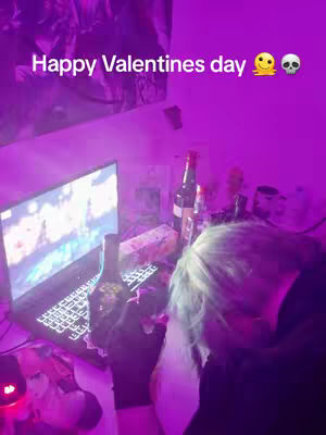 The cover image shows a person in a room bathed in a purple glow, with several items on a desk, including a laptop, bottles, and a hand holding an object. The foreground is dominated by the side view of a person with hair covering most of the face. The lighting is dim, and the overall composition is slightly cluttered. The text overlay reads, "Happy Valentines day"