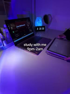 A softly lit interior with a laptop open on a desk, a glowing blue light, and an iPad. Text overlayed indicates a study session from 9 p.m. to 2 a.m.