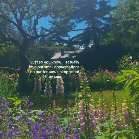 A serene outdoor scene. Lush greenery fills the foreground with various flowers, leading the eye towards a house nestled among tall trees under a blue sky. The composition is vertical, typical of social media posts.
