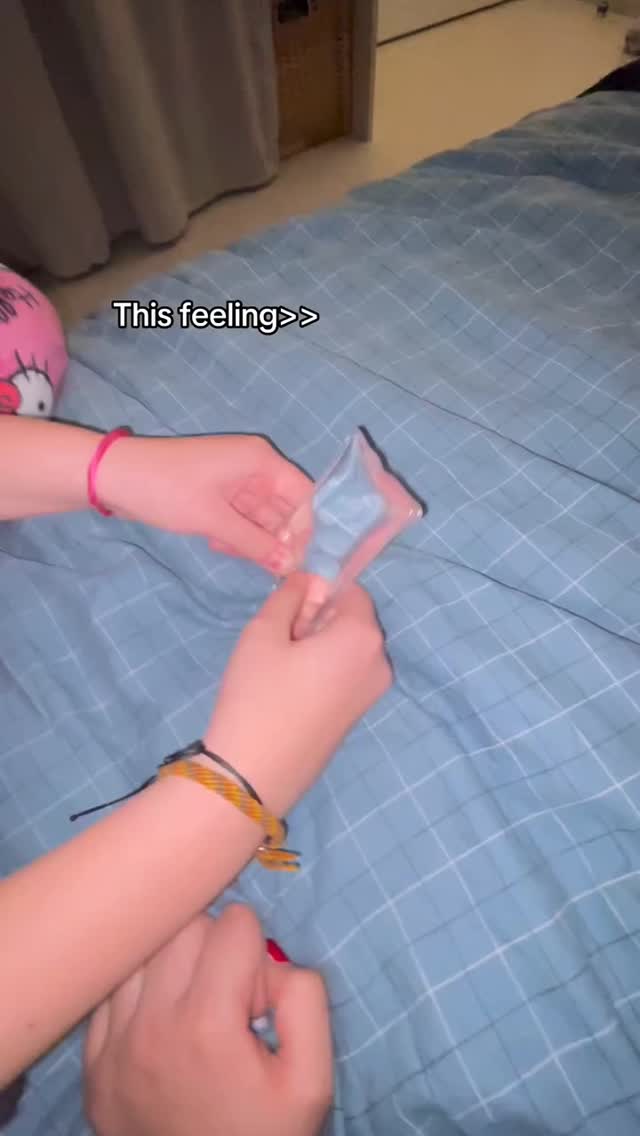 A video cover image shows a person's hands holding a small, clear plastic bag filled with blue pills against a blue plaid bedspread. The bag is held open, and the focus is on the hands and the contents of the bag. Text overlayed reads "This feeling>>".