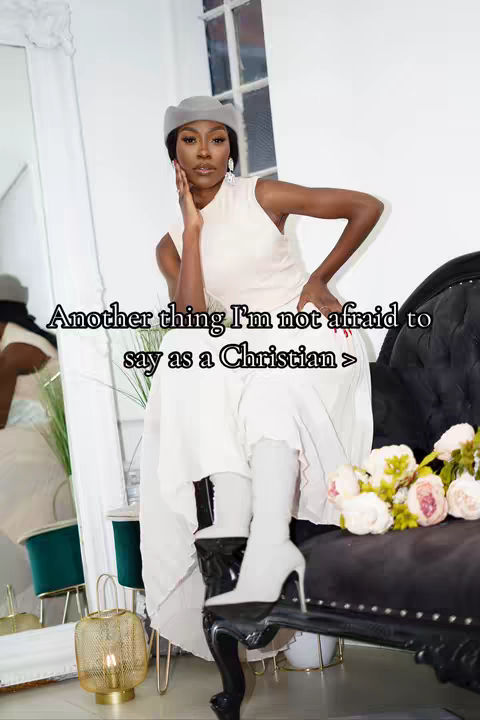 A woman in a white dress and hat is seated on a black chaise lounge. She is holding her hand up to her face and the text overlay on the image read 'Another thing I'm not afraid to say as a Christian >'.