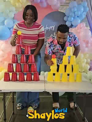 Two people are seen at a party, each set up with a pyramid of dixie cups and ready to play a game.