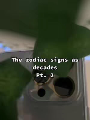 The cover image shows a close-up shot of a phone's camera lens area with a leafy plant partially obscuring the view. The image is overlaid with white text that reads 'The zodiac signs as decades Pt. 2'. The background is blurred, with green hues from the plant.