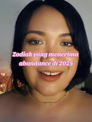 A close-up shot of a woman smiling, with a pink text overlay. The woman has dark hair, brown eyes, and is wearing a gold necklace. The background is blurred, suggesting an indoor setting.