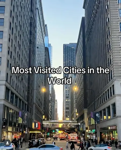 A city street scene dominated by tall buildings on either side, narrowing towards the horizon. The central focus is a multi-lane road with traffic, leading up to a brighter area in the distance, possibly the horizon or a gateway. Text is overlayed in the middle, white text on a black background.