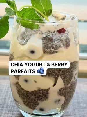 A close-up of a parfait in a clear glass. Layers of chia seed pudding, yogurt, and berries are visible. Mint leaves decorate the top, and text overlays appear in a white box.