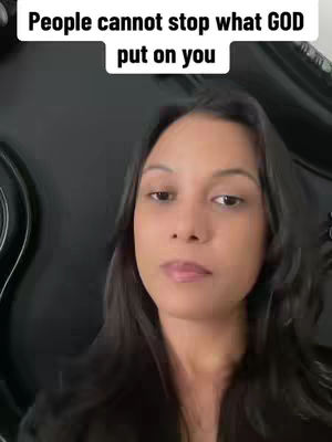 A woman with dark hair is looking directly at the camera. The top of a text overlay is visible above her head. The background is out of focus and dark.