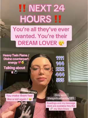 A woman with dark hair and glasses is holding a tarot card, while also holding up a sign. The image contains a pink background, text overlays, and numerical sequences.