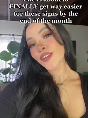 A woman with long dark hair is looking at the camera with a friendly smile, overlaid with text. She has makeup on and a small nose piercing, and a necklace. Behind her, there is a blurred background with some plants.