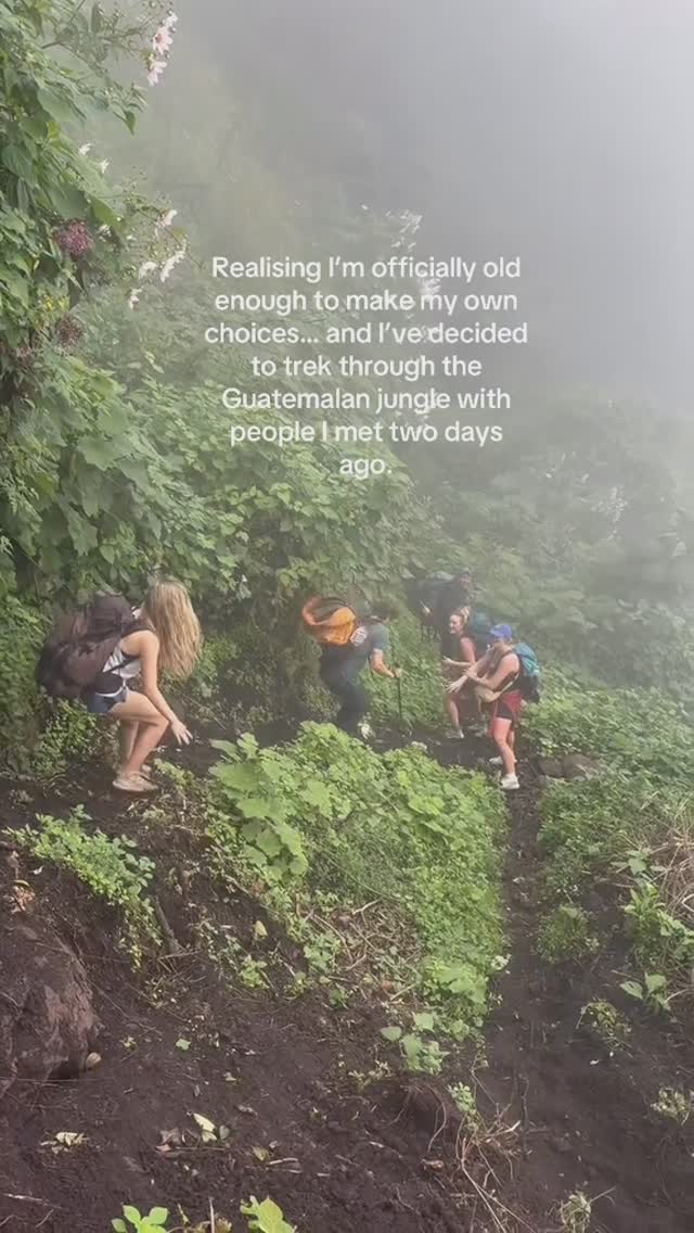The image shows a group of people hiking through a lush, green, mountainous landscape. The trail is narrow and leads upward. Overlaid on the image is text.