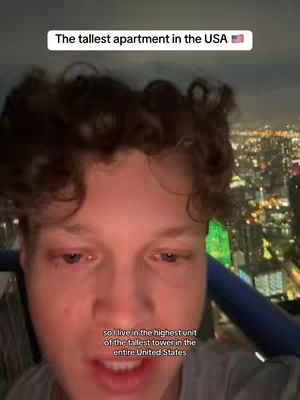 A young man is centered in the frame, close up, with a city skyline visible above his head. A text overlay states, "The tallest apartment in the USA".