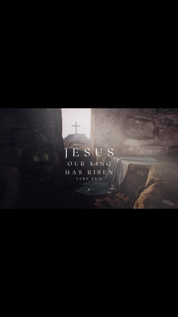 The image shows an open tomb with a bright light emanating from within, suggesting the resurrection of Jesus. A cross is visible in the distance, and text overlayed reads 'JESUS OUR KING HAS RISEN' along with the reference 'LUKE 24:6'. The color scheme is muted with neutral tones, focusing on the contrast of light and shadow to create a reverent and hopeful atmosphere.