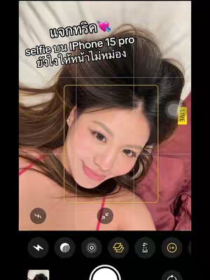 The cover image shows a woman lying in bed and posing as a selfie. A camera interface is on the screen with the phone's icons at the bottom. Text overlays are added over the image, in a Thai language.