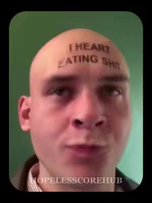 A close-up shot of a bald man's face with a humorous tattoo on his forehead. The background is a plain green.