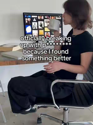 A woman is sitting in a chair in front of a computer displaying multiple images. She is holding a white mug and appears to be at home. Text overlayed on the image that says: "officially breaking up with p******** because I found something better"