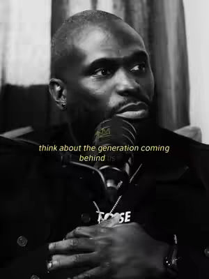 A close-up, grayscale image of a Black man speaking into a microphone. The man is wearing a dark jacket and a necklace. Yellow text at the bottom reads, 'think about the generation coming behind us.' The overall composition is focused and serious.