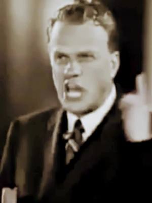 A sepia-toned close-up of a man speaking passionately with his mouth open, his right index finger raised, and his eyes looking slightly off-camera.