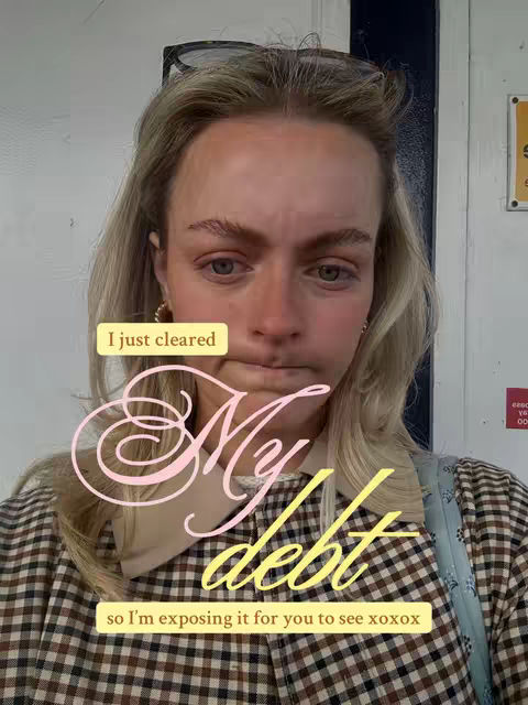 A medium shot shows a young woman with blonde hair looking at the camera with a worried or pensive expression. She has fair skin and is wearing some light makeup. Sunglasses are positioned on top of her head. Text overlays appear, with "I just cleared" in a yellow rectangle at the top left corner followed by a stylized "My debt" in pink and yellow script in the middle and "so I'm exposing it for you to see xoxox" in the bottom. The background includes a building entrance with tan wall and a door, and a sign in the upper right corner with some text, and a partial glimpse of exterior surroundings.
