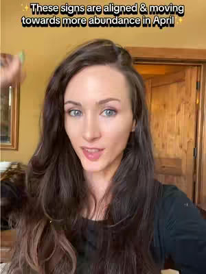 A woman with long, dark wavy hair is looking towards the camera. She is wearing a black top. Overlayed text is at the top of the frame.
