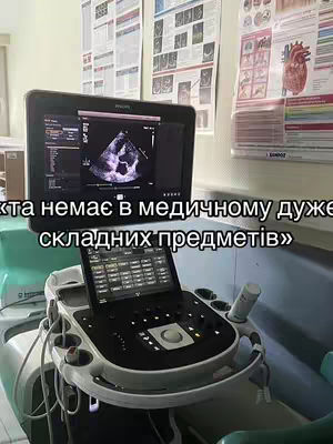An image showing an ultrasound machine with a display showing a heart ultrasound image. Text overlays are superimposed on the image. The background includes medical charts and a sterile environment.