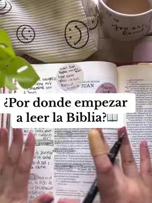 The image shows a book open on a table with the title of "¿Por donde empezar a leer la Biblia?" written on a white bar, it has markers and stickers and a cup with white and pink elements.