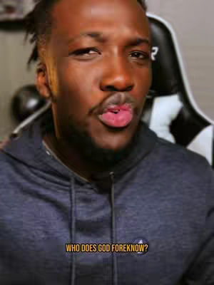 A close-up shot of a Black man making a kissing face toward the camera. He wears a blue hoodie and has short dreadlocks. The background includes a gaming chair and a dark, blurred area. A text overlay at the bottom reads, "WHO DOES GOD FOREKNOW?"