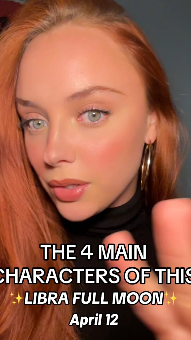 A close-up shot of a woman with fair skin, light green eyes, and auburn hair. Text overlaid on the image reads: "THE 4 MAIN CHARACTERS OF THIS" followed by "✨ LIBRA FULL MOON ✨" and "April 12". The woman is wearing a black turtleneck and gold hoop earrings; her expression is neutral with a slight smile playing on her lips.